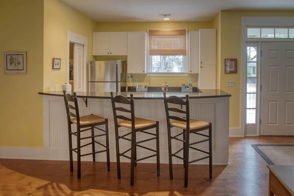 A kitchen with a bar and three chairs in it