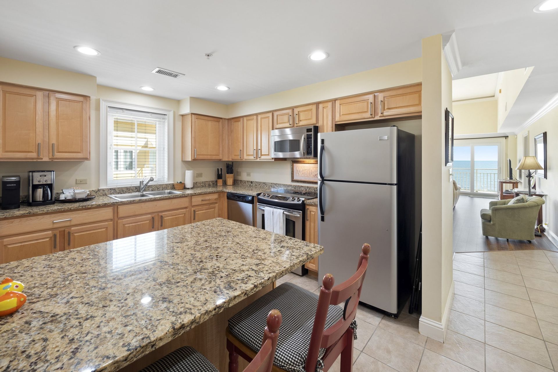 A kitchen with granite counter tops , stainless steel appliances , and a refrigerator.