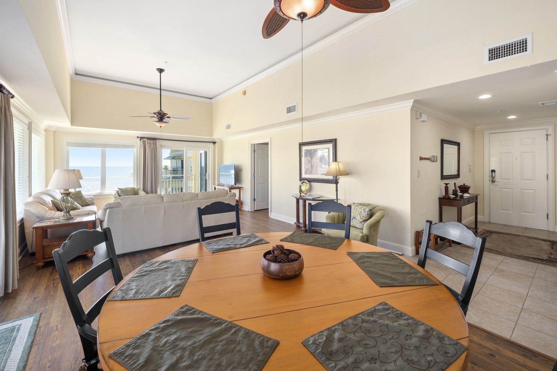 A living room with a dining table and chairs and a ceiling fan.