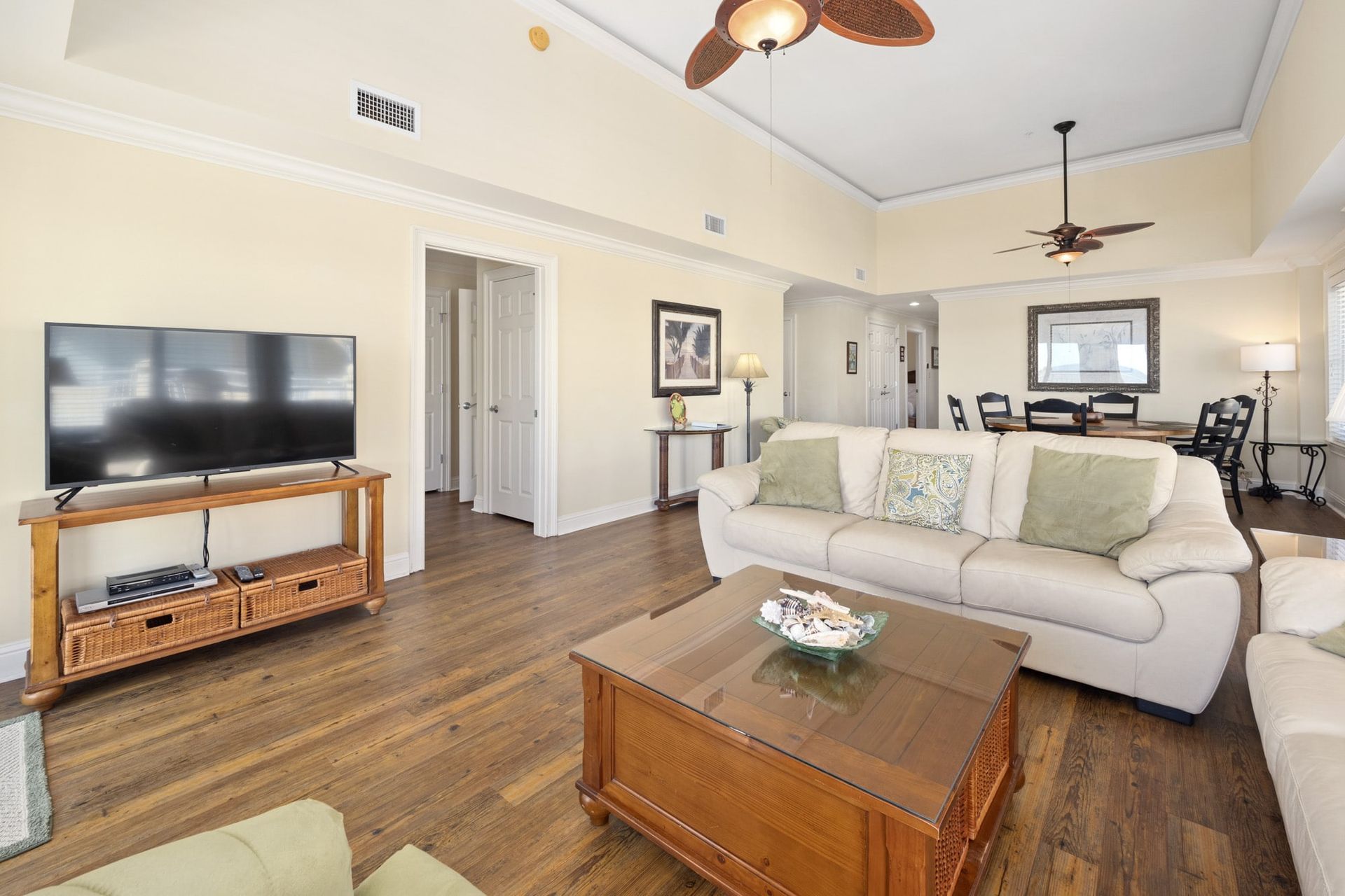 A living room with a couch , coffee table , television and ceiling fan.