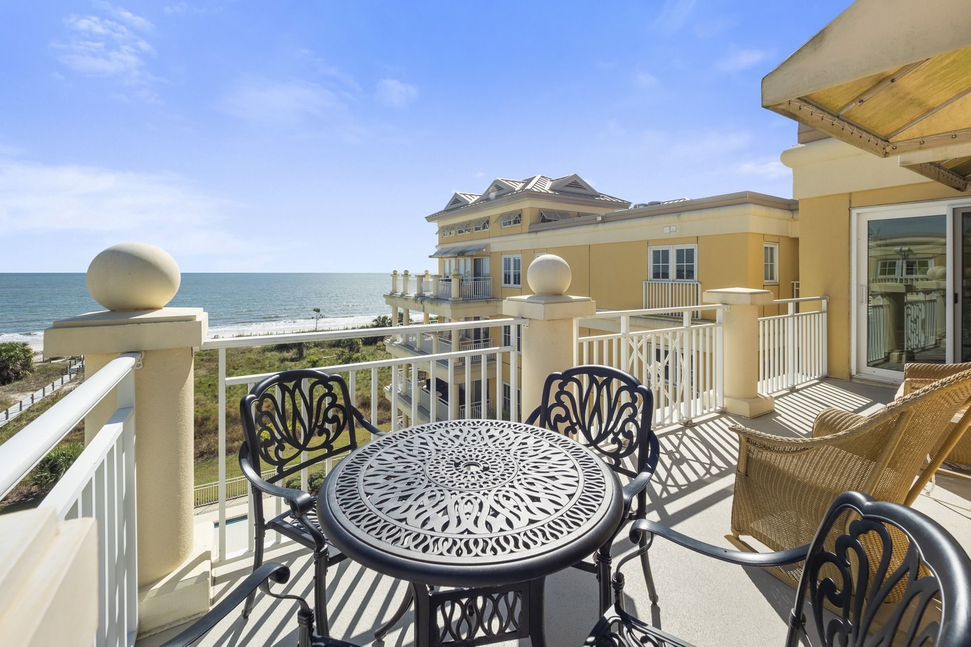 A balcony with a table and chairs overlooking the ocean.