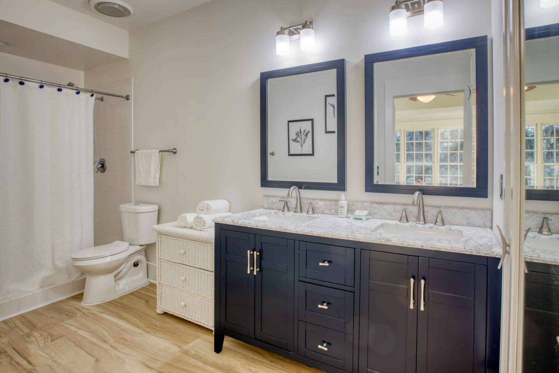 A bathroom with two sinks , a toilet , and two mirrors.