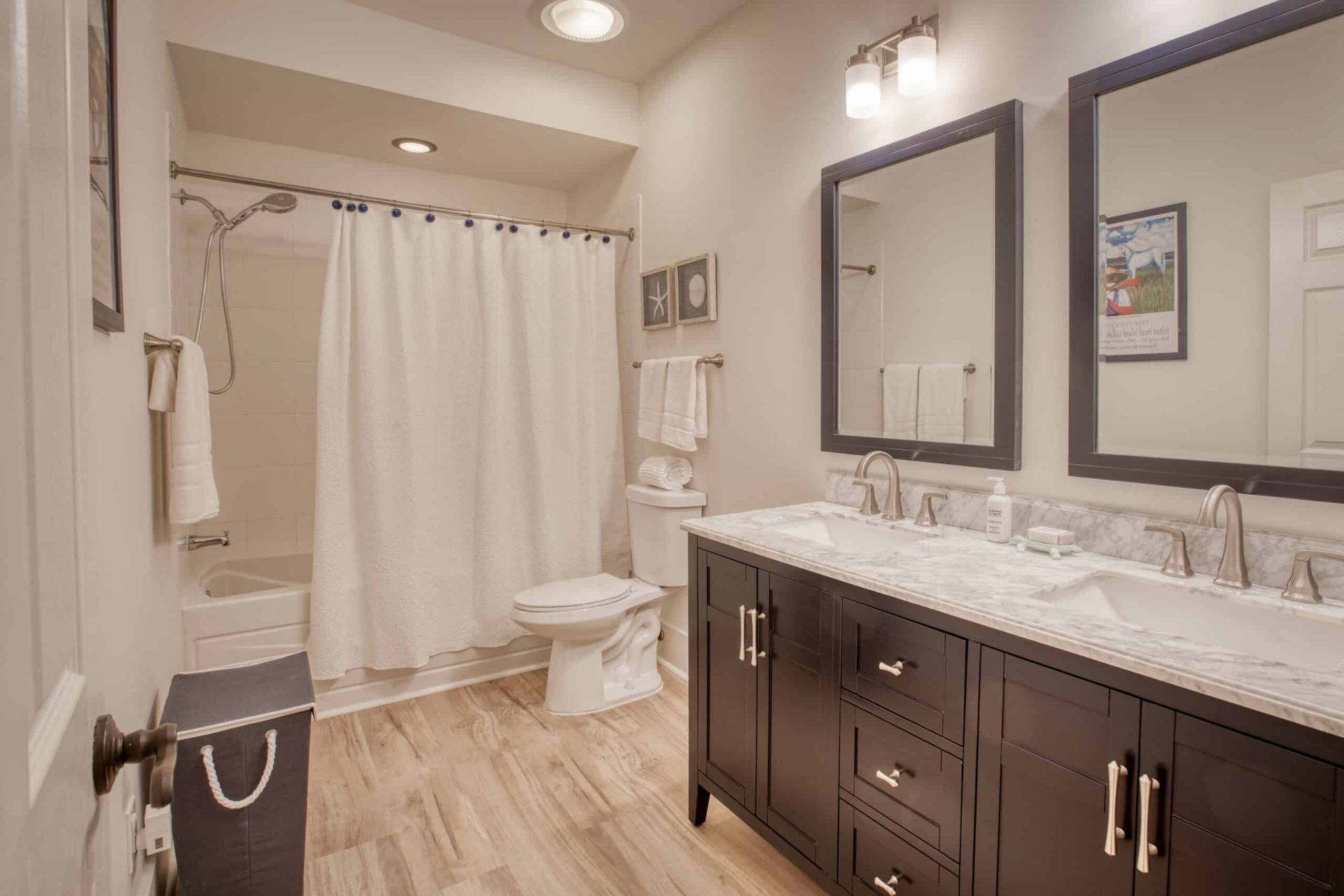 A bathroom with two sinks , a toilet , and a shower curtain.