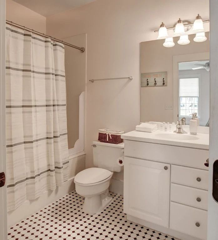 A bathroom with a toilet a sink and a shower curtain