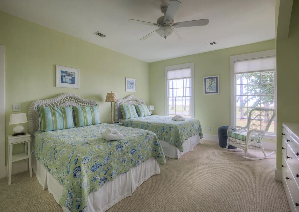 A bedroom with two beds and a ceiling fan.