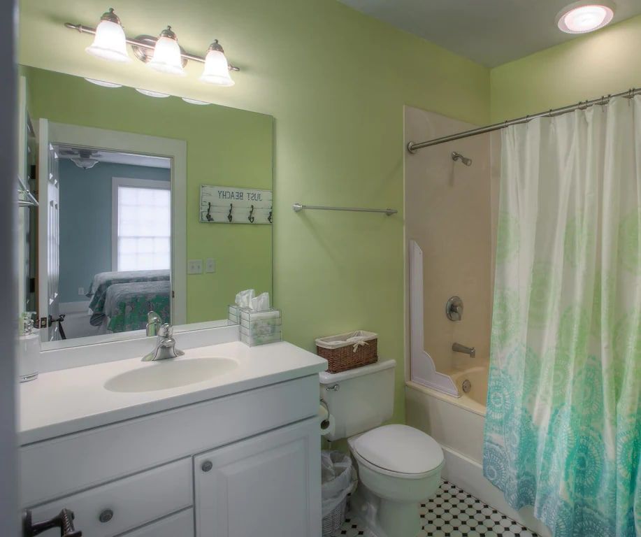 A bathroom with a toilet , sink , shower and mirror.