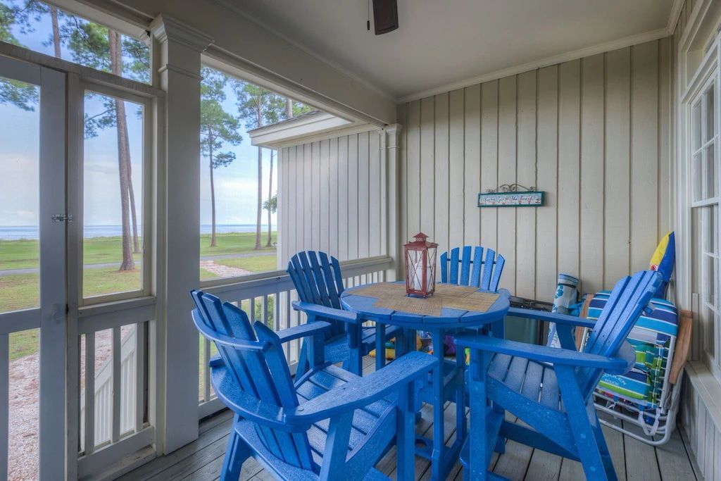 A screened in porch with blue chairs and a table.