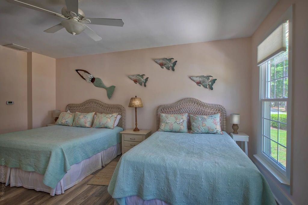 A bedroom with two beds and a ceiling fan.
