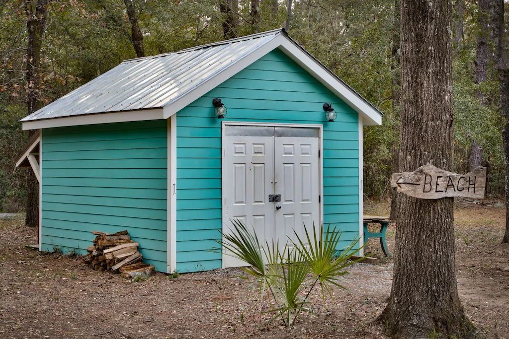 A blue and white shed with a sign that says beach in front of it.