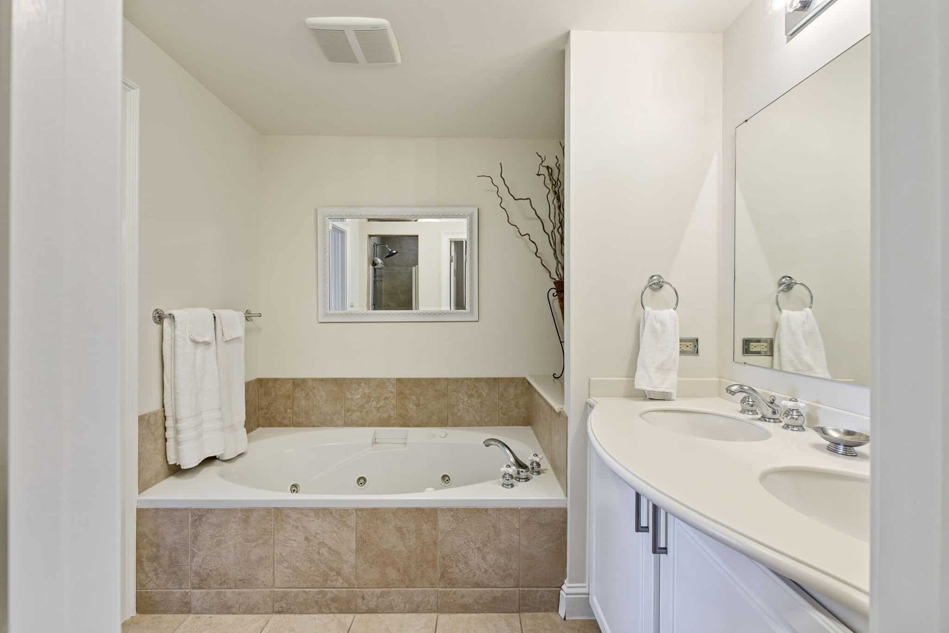 A bathroom with a jacuzzi tub , sink and mirror.