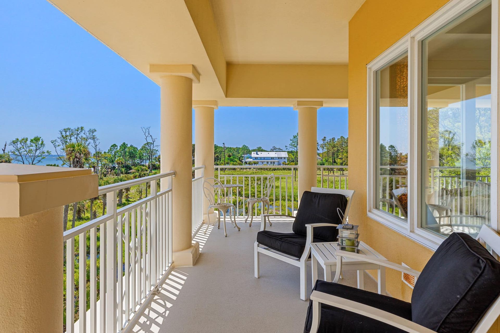 A balcony with two chairs and a table with a view of trees