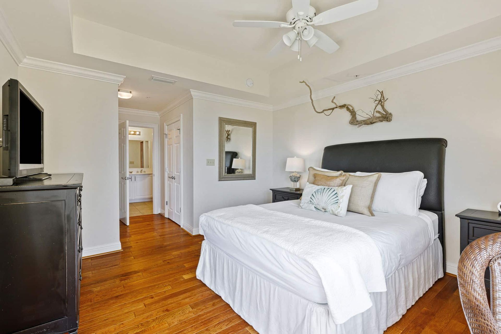 A bedroom with a king size bed , a television , a mirror and a ceiling fan.