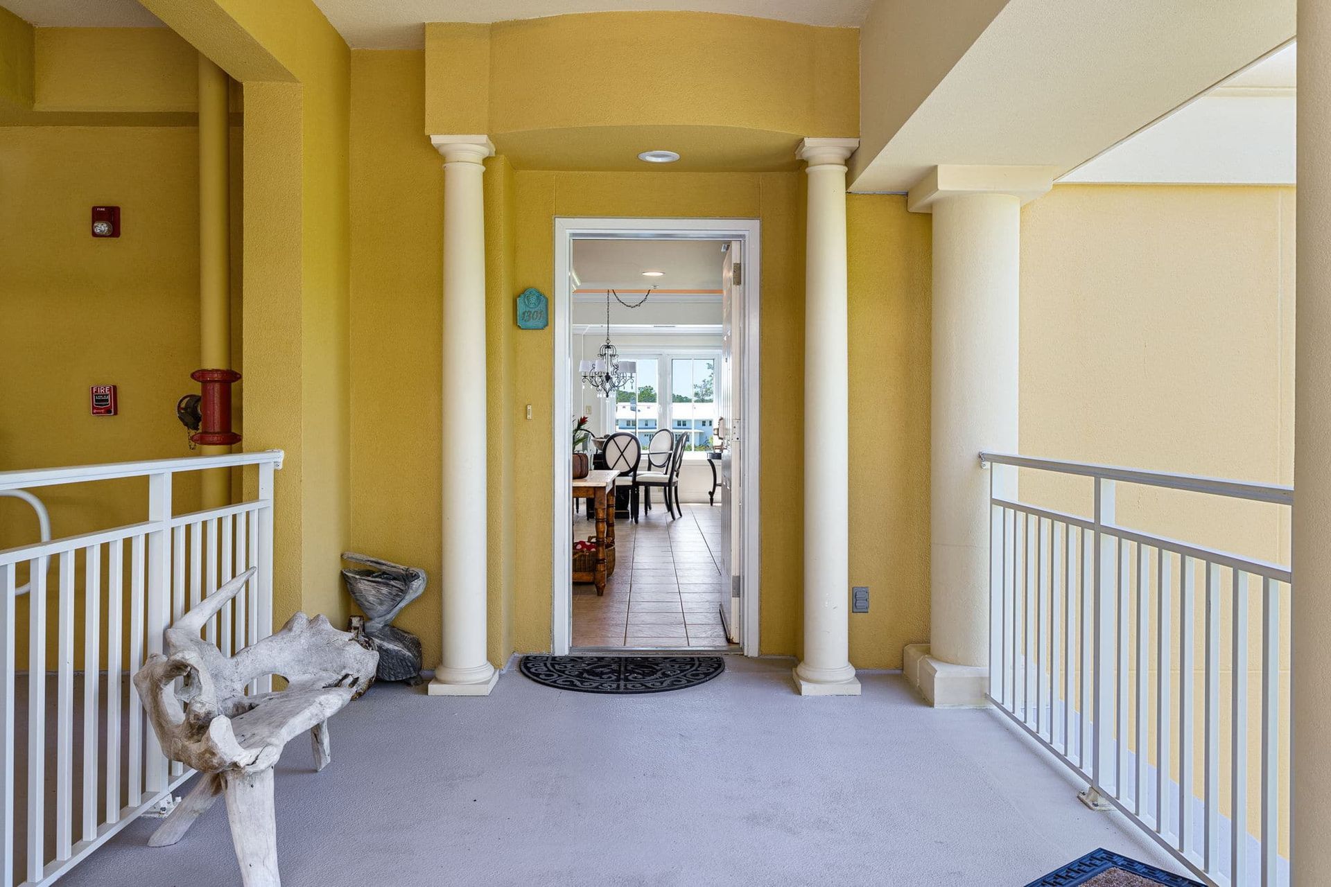 A balcony with a bench and a doorway leading to a living room.
