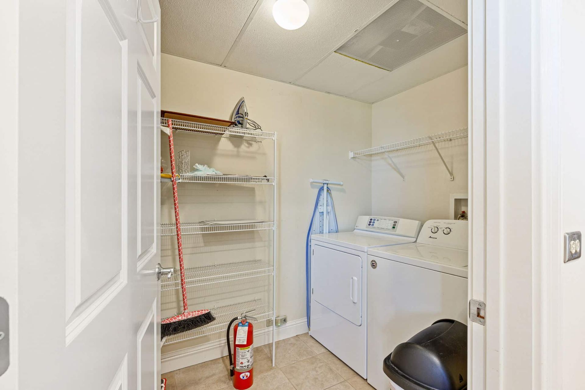 A laundry room with a washer and dryer and a fire extinguisher.