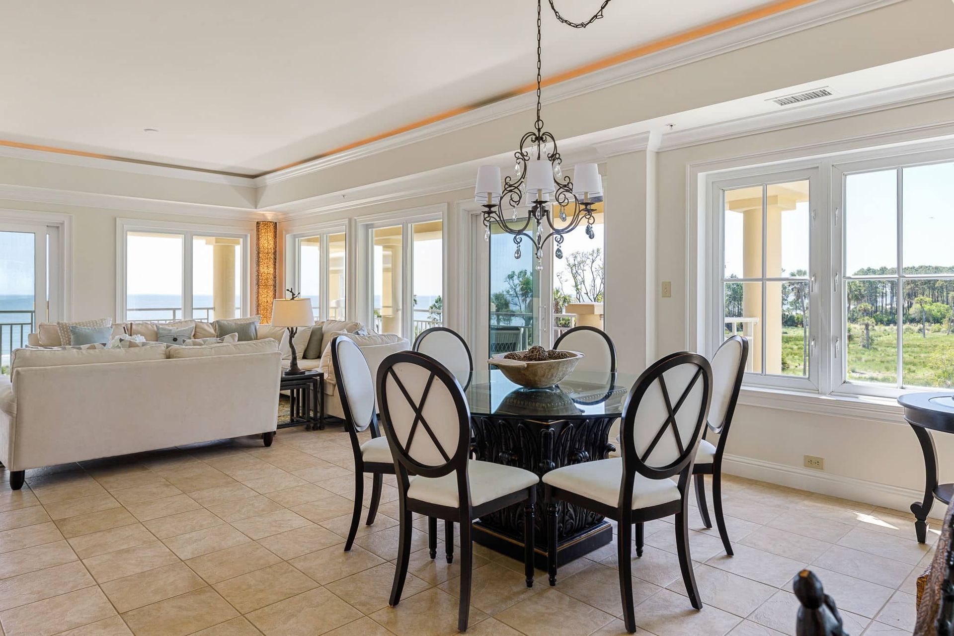A living room with a dining table and chairs and a chandelier.