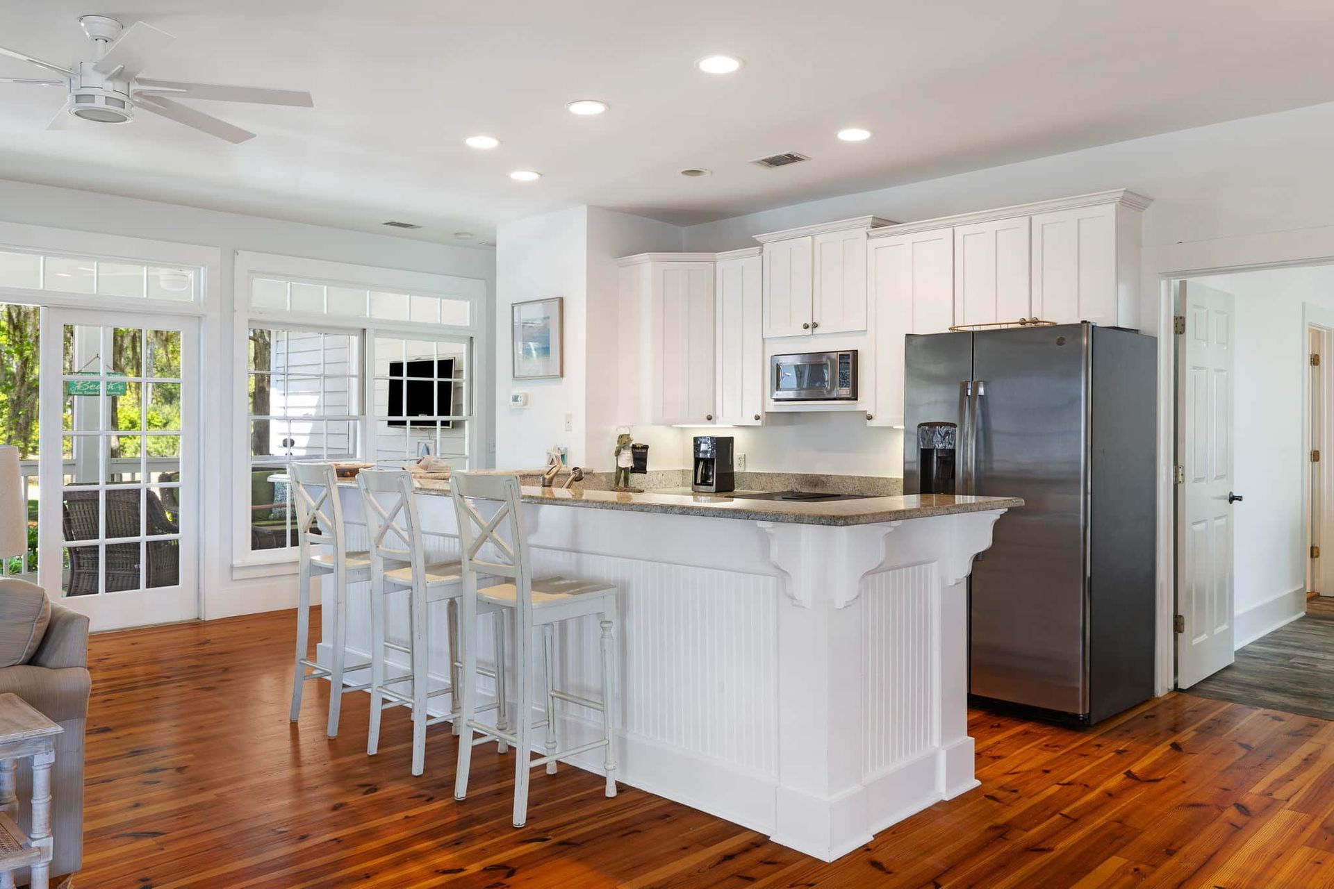 A kitchen with white cabinets , stainless steel appliances , and hardwood floors.