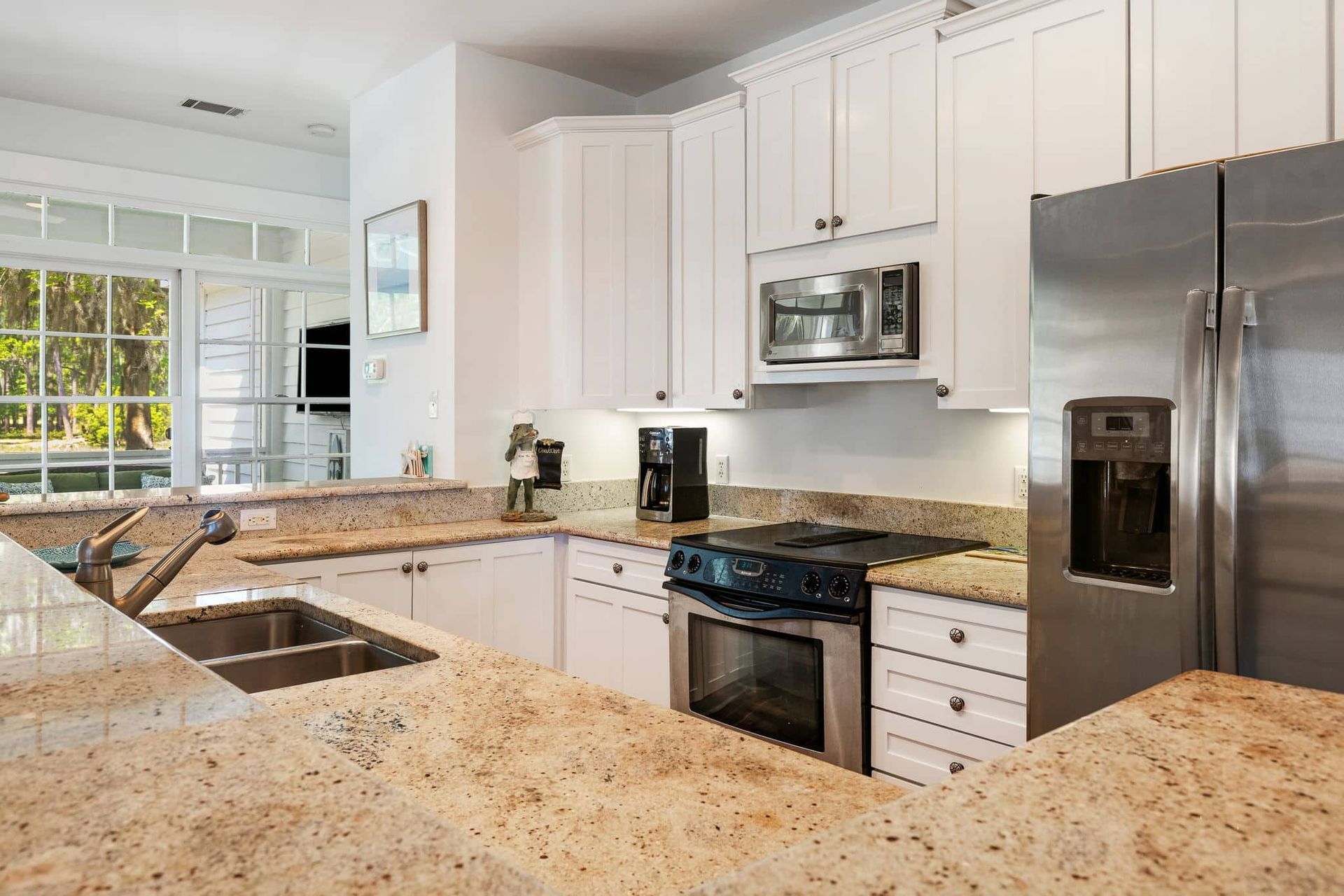 A kitchen with granite counter tops , stainless steel appliances , and white cabinets.