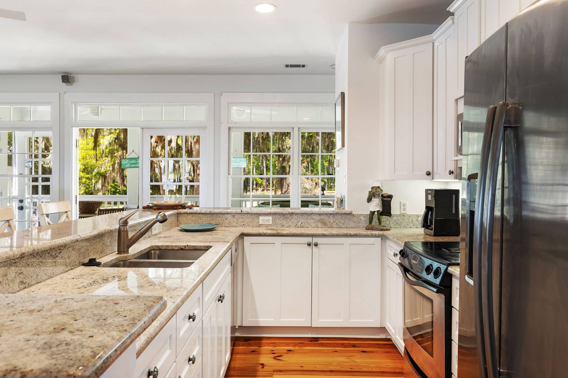 A kitchen with granite counter tops , stainless steel appliances , and white cabinets.