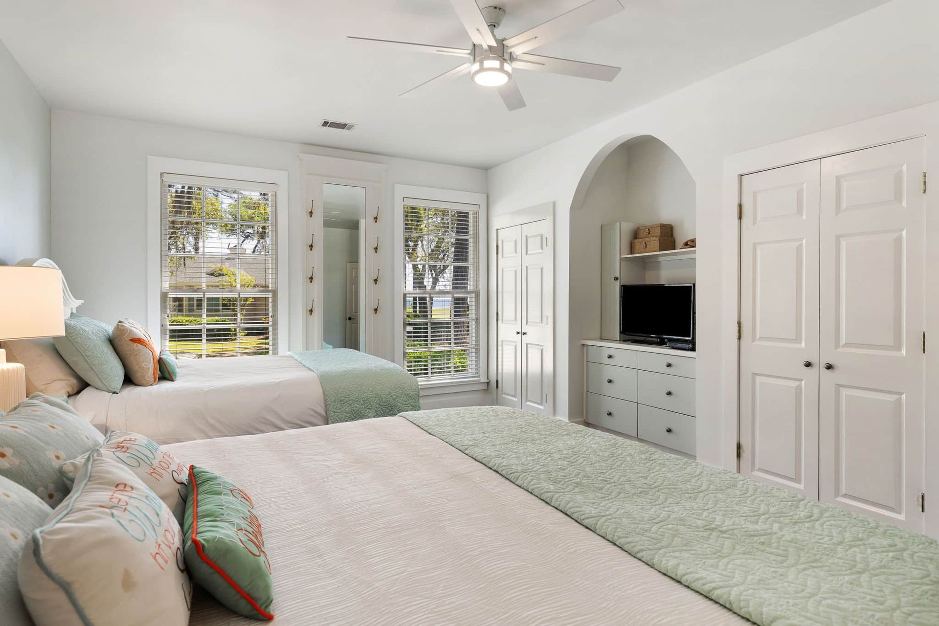 A bedroom with two beds and a ceiling fan.