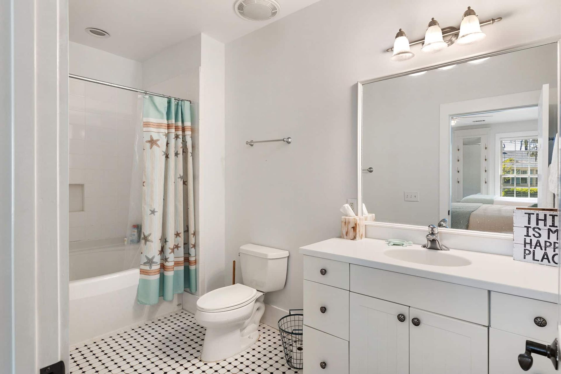 A bathroom with a toilet , sink , shower and mirror.