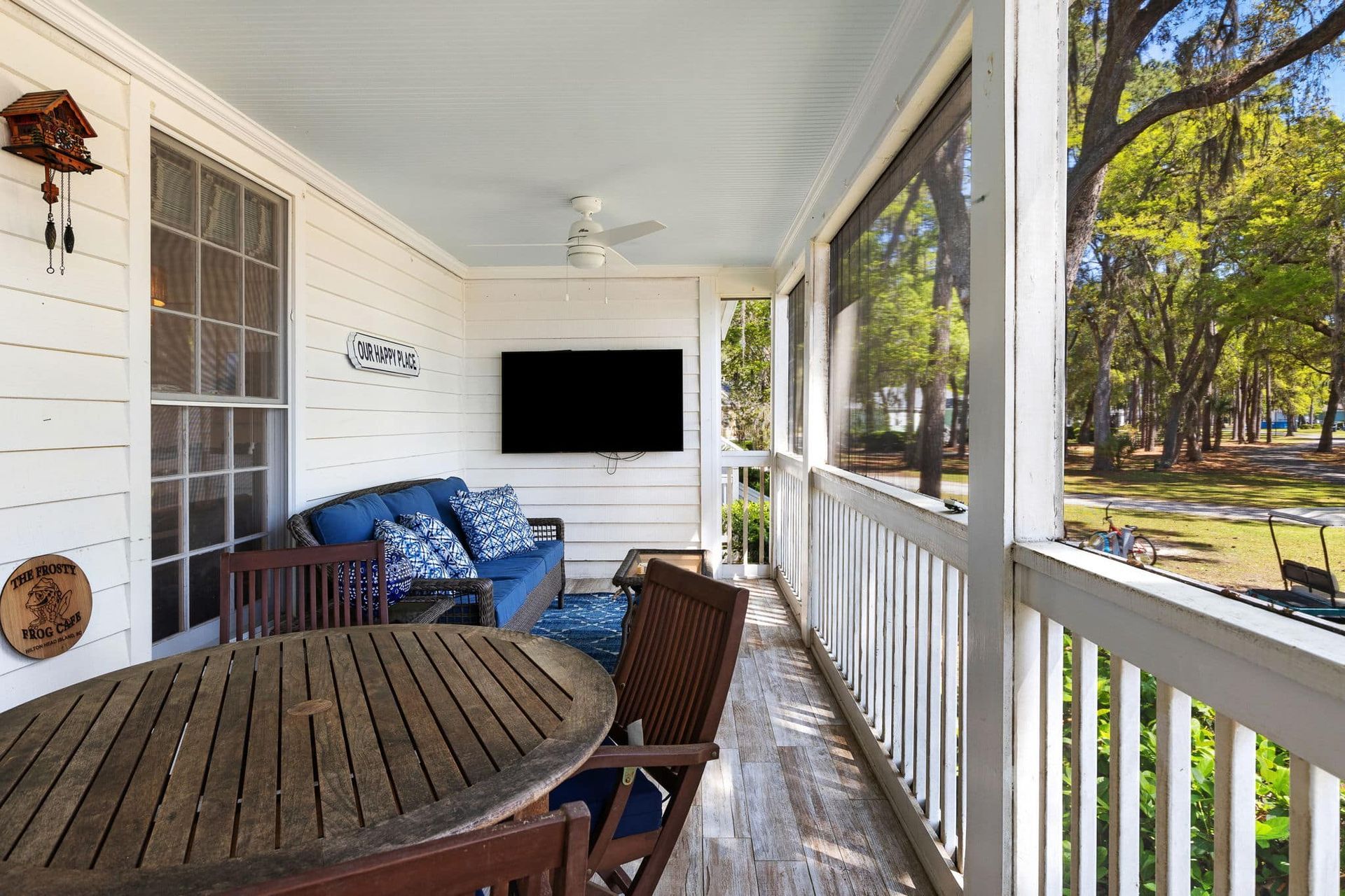 A screened in porch with a table and chairs and a flat screen tv.