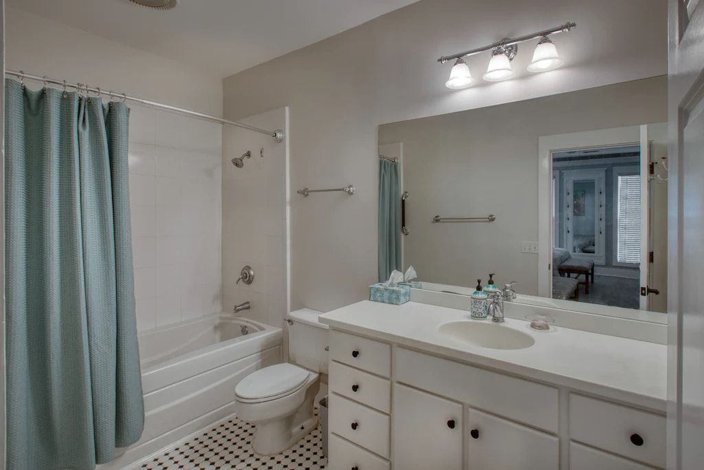 A bathroom with a toilet , sink , tub and mirror.