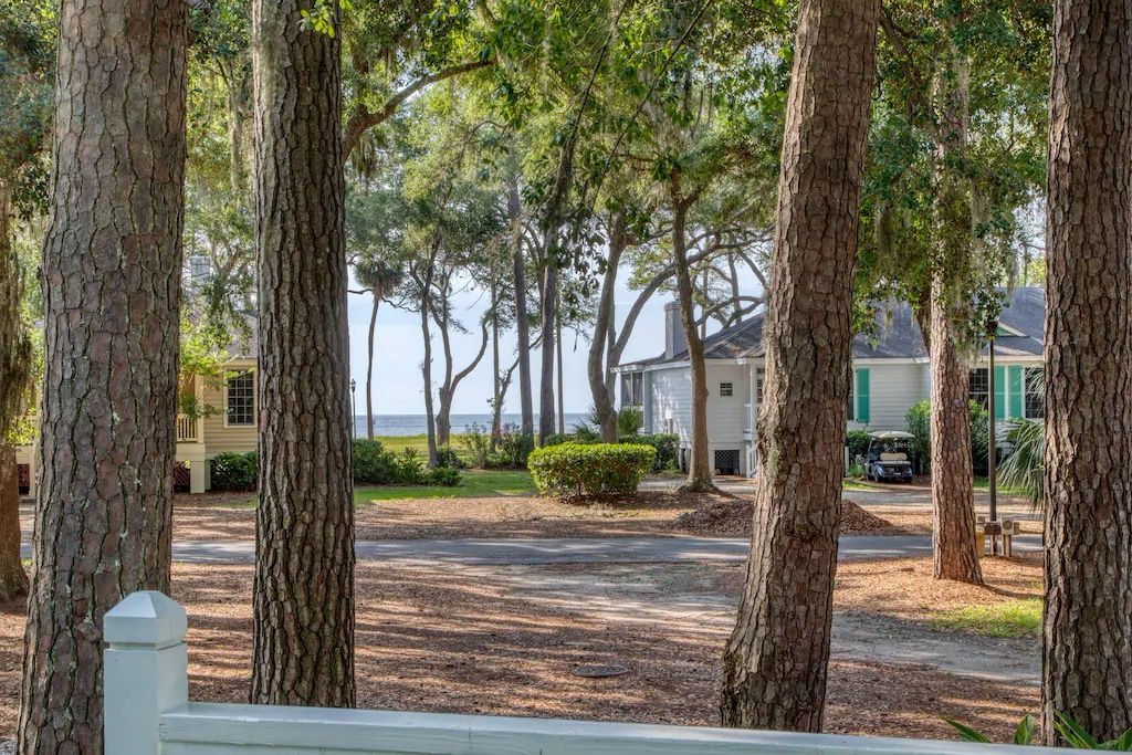 A view of a house through a fence surrounded by trees.
