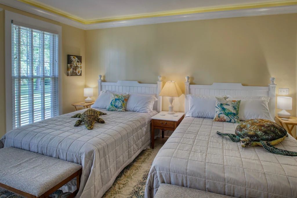 A bedroom with two beds , a bench and a window.