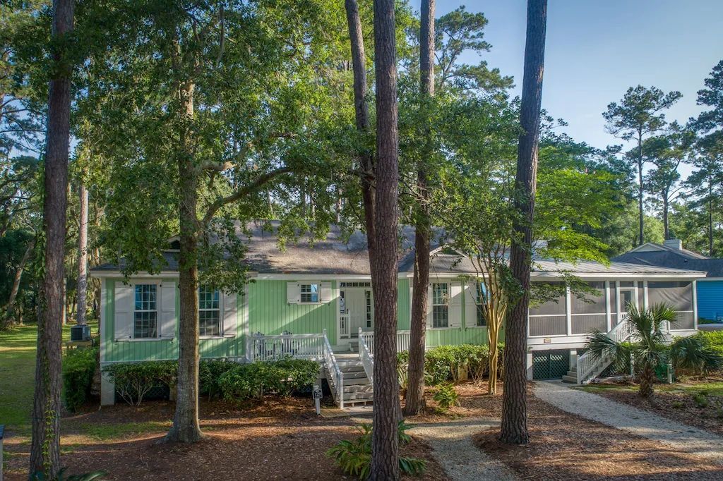 A green house is surrounded by trees on a sunny day.