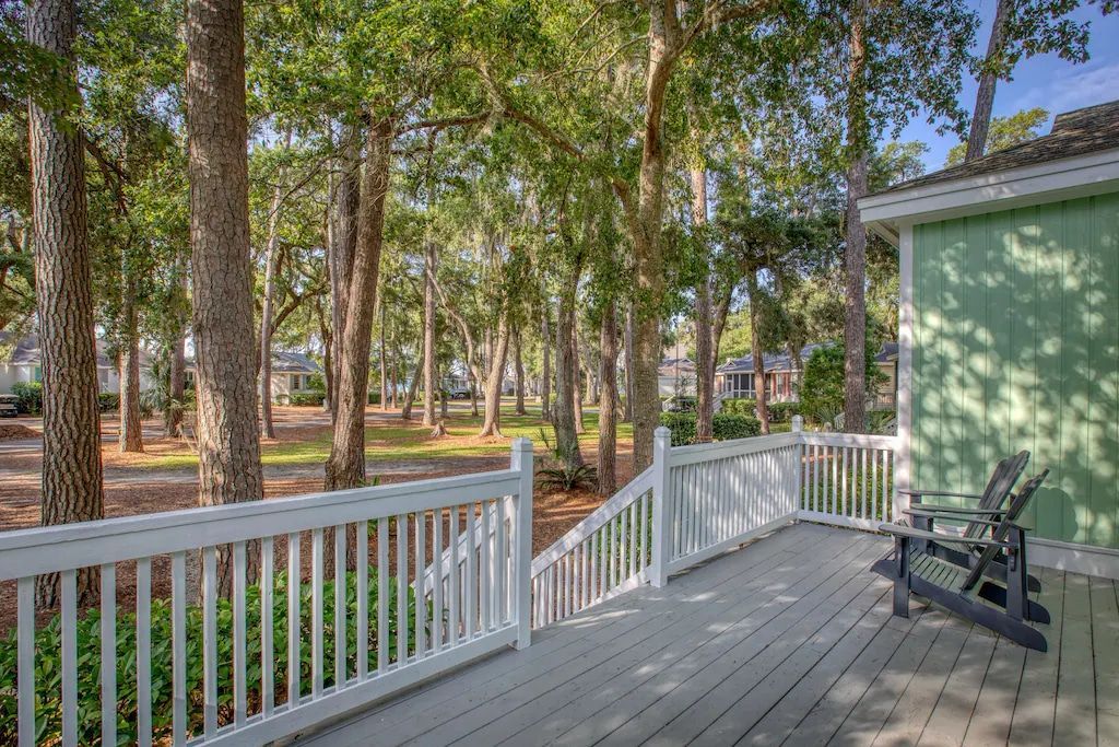 A deck with a chair and stairs leading up to it surrounded by trees.
