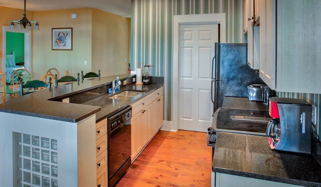 A kitchen with granite counter tops , a stove , a refrigerator , and a sink.