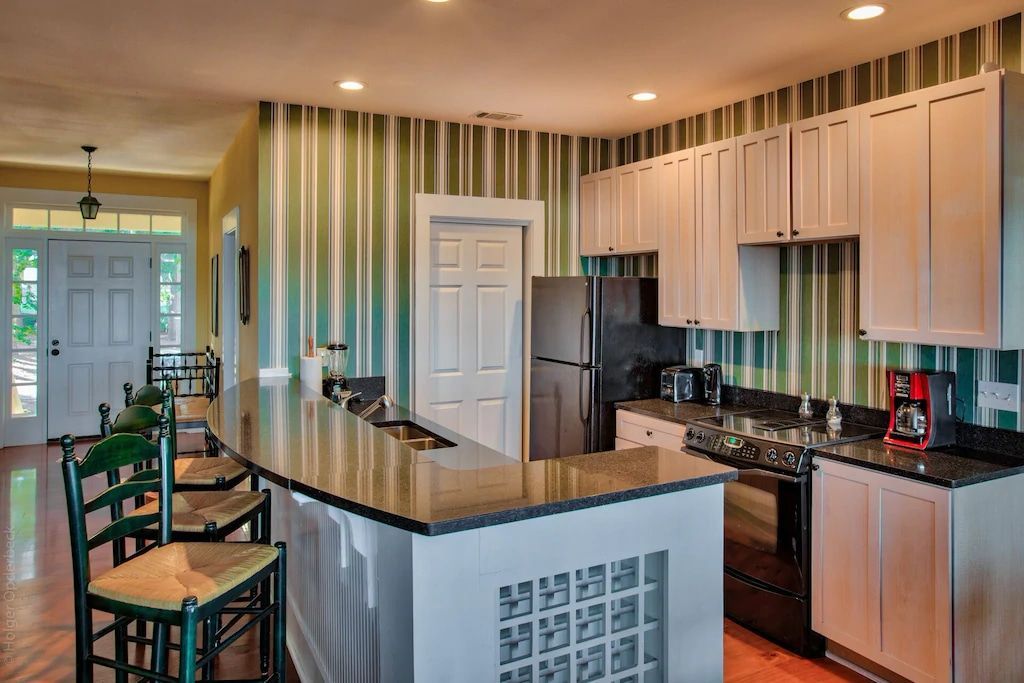 A kitchen with stainless steel appliances , granite counter tops , and striped wallpaper.