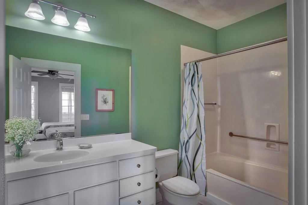 A bathroom with a toilet , sink , shower and mirror.