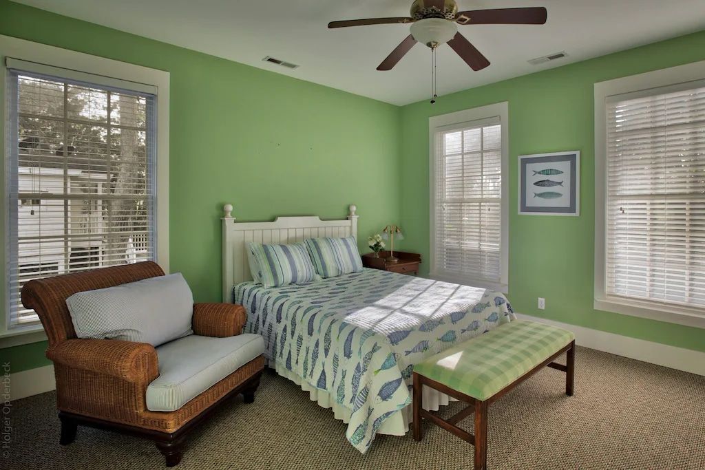 A bedroom with green walls and a ceiling fan