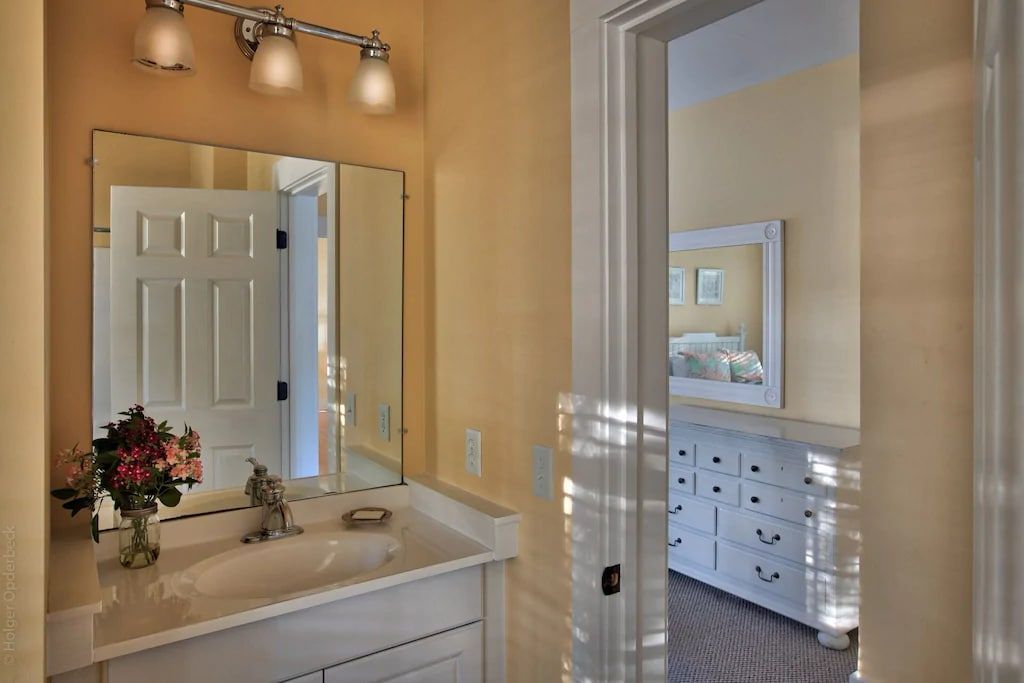 A bathroom with a sink , mirror and dresser.