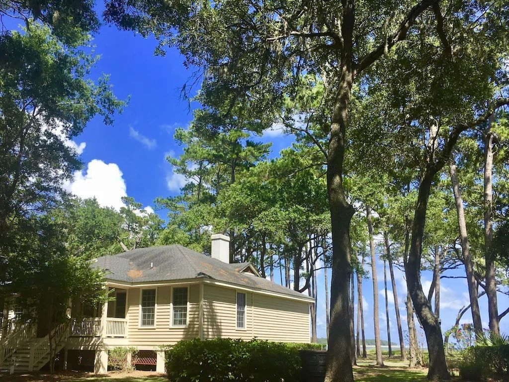 A white house is surrounded by trees on a sunny day.