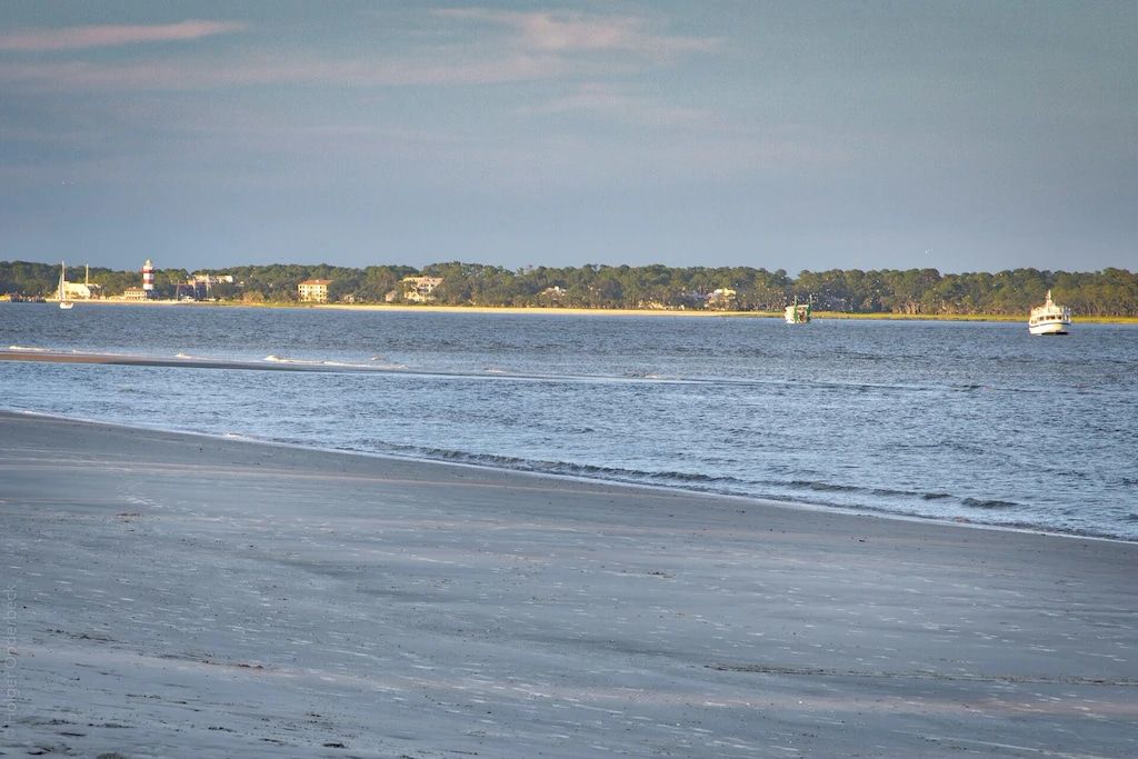 A boat is floating on top of a body of water near a beach.