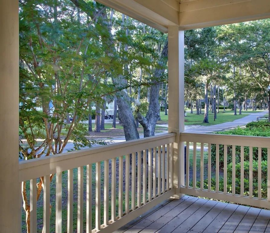A porch with a white railing and trees in the background