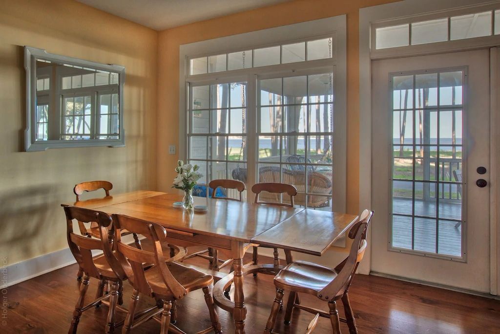 A dining room with a table and chairs and lots of windows
