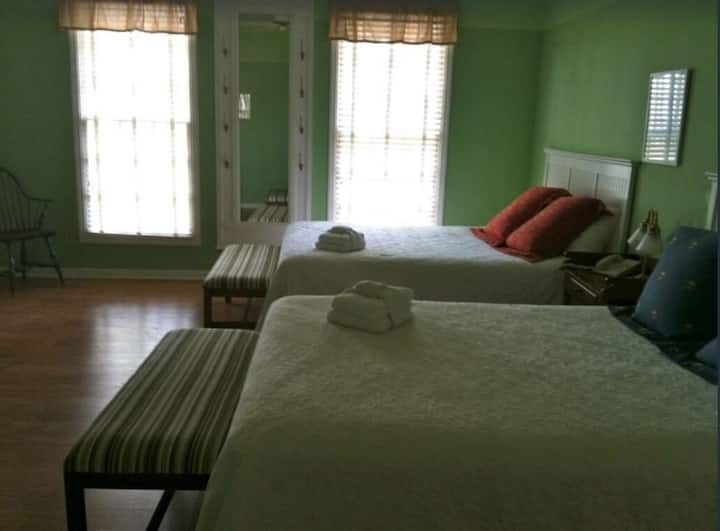 A hotel room with two beds and a bench