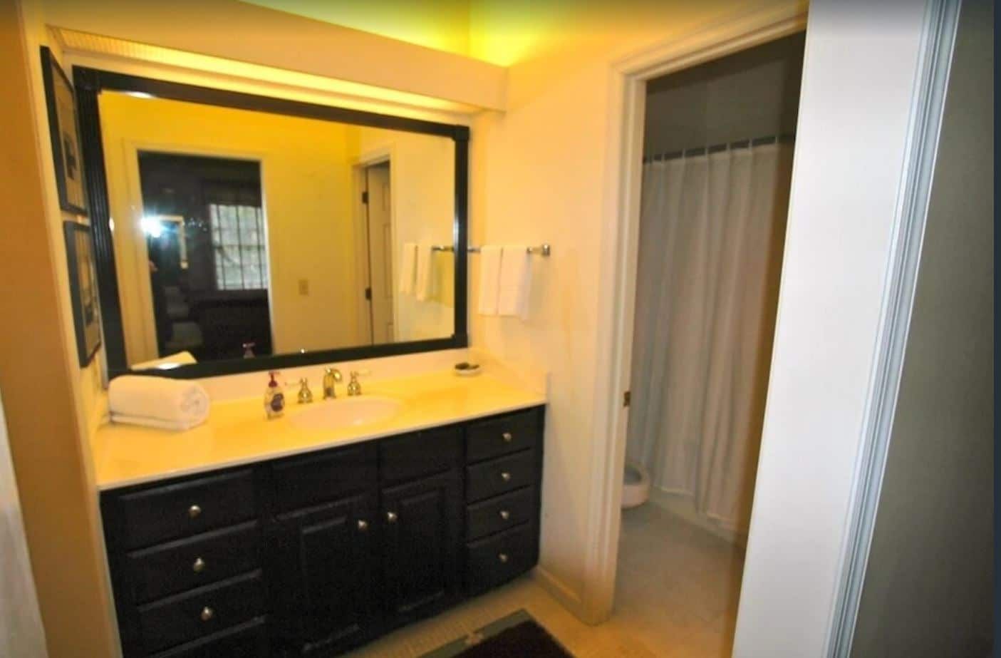 A bathroom with black cabinets and a large mirror