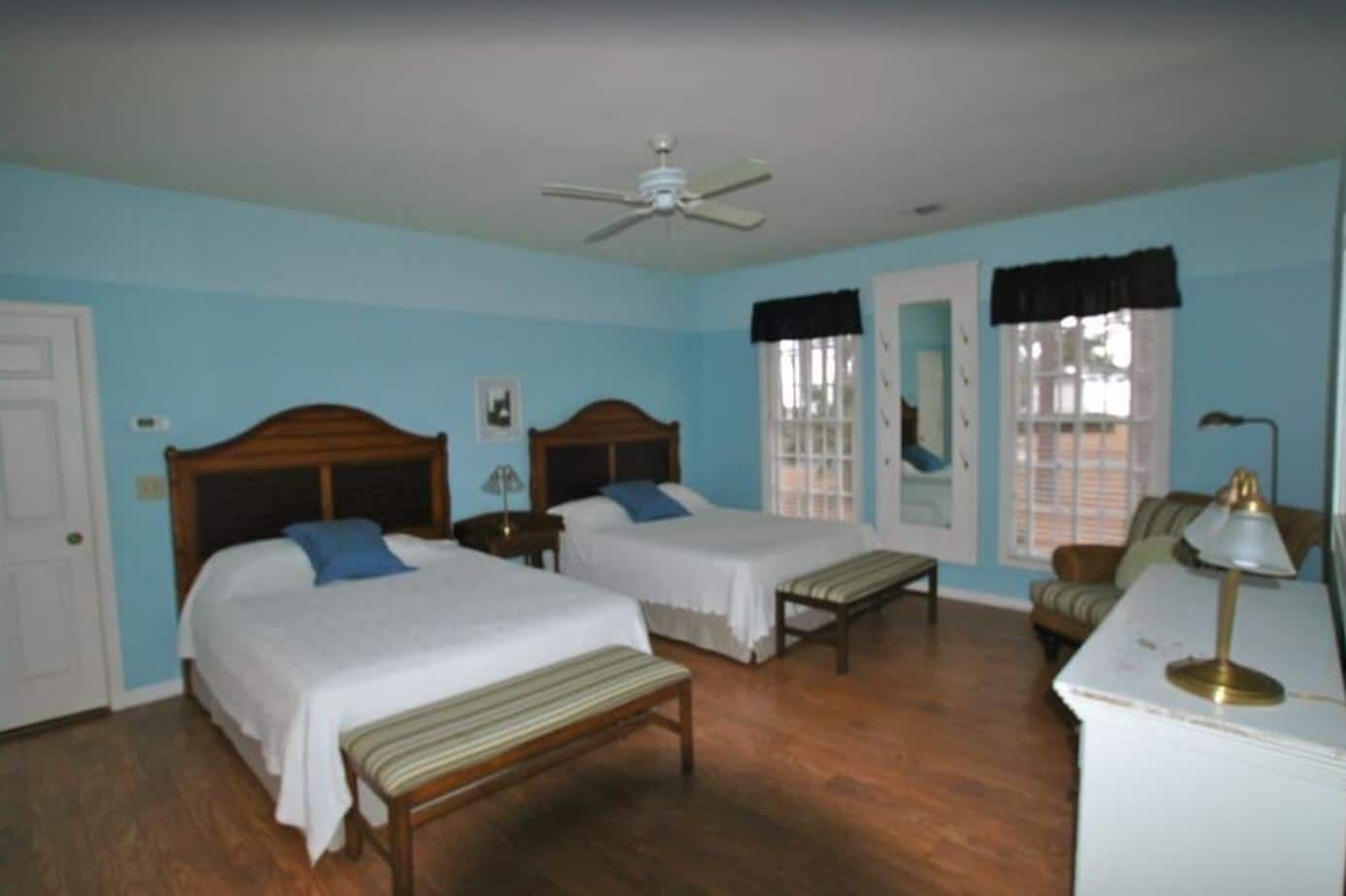 A bedroom with two beds a bench and a dresser