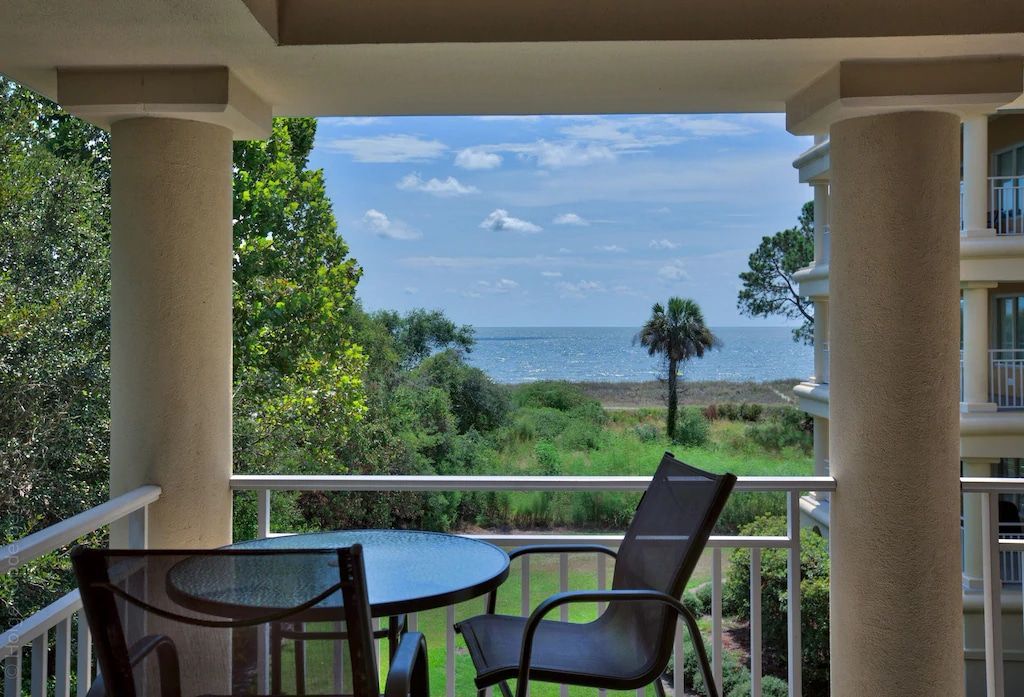 A balcony with a table and chairs overlooking the ocean