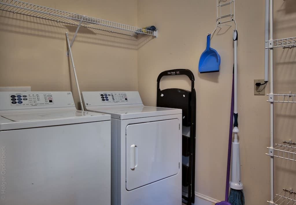 A laundry room with a washer and dryer and a mop.