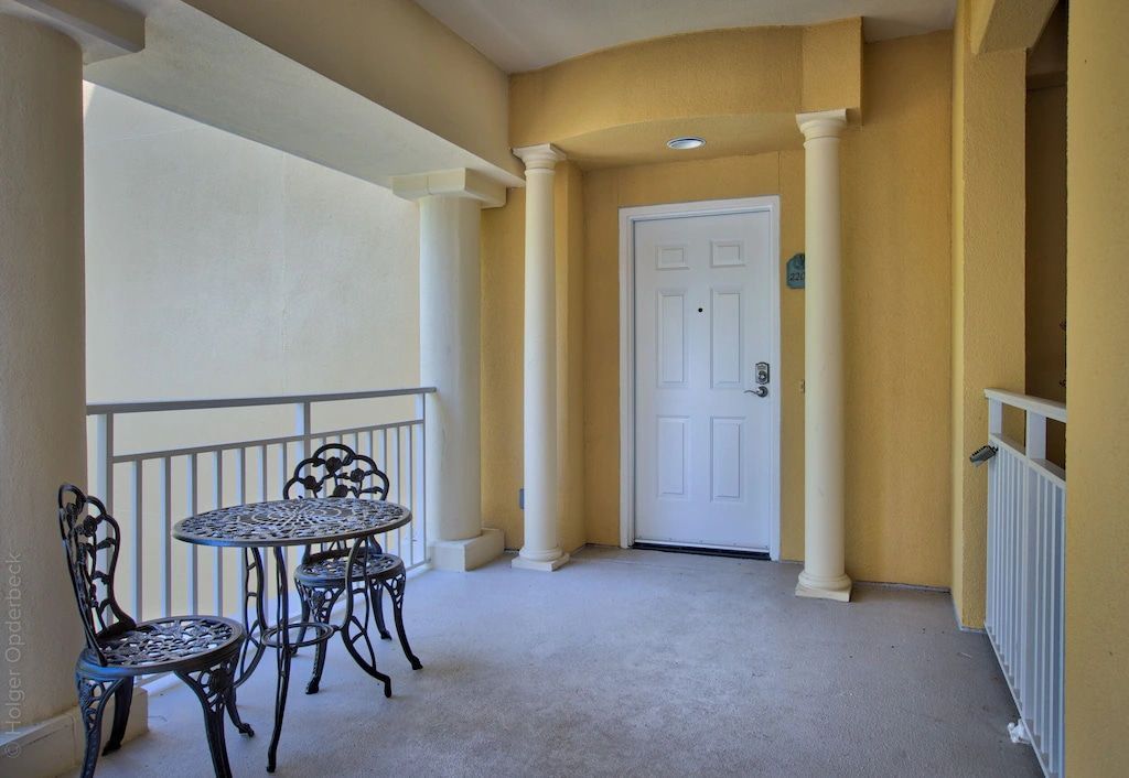 A balcony with a table and chairs in front of a door