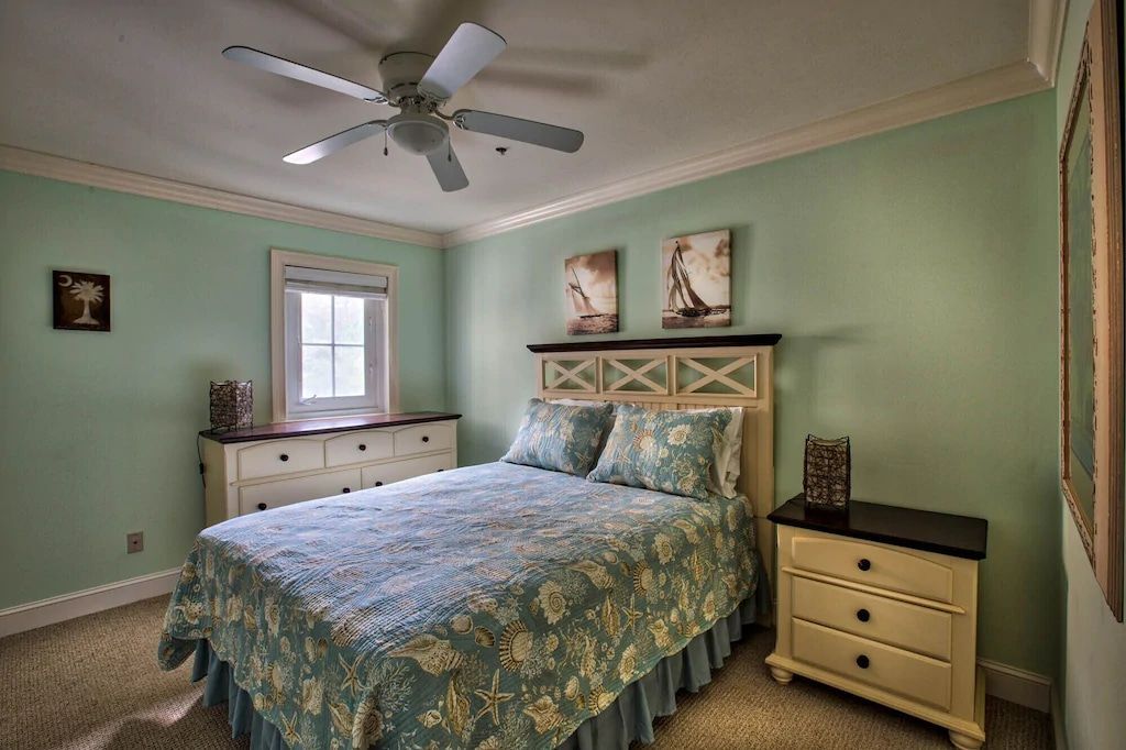 A bedroom with a bed , dresser , nightstand and ceiling fan.