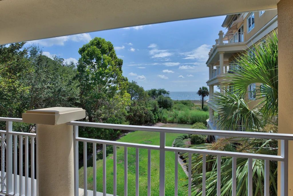 A balcony with a view of a lush green field and the ocean