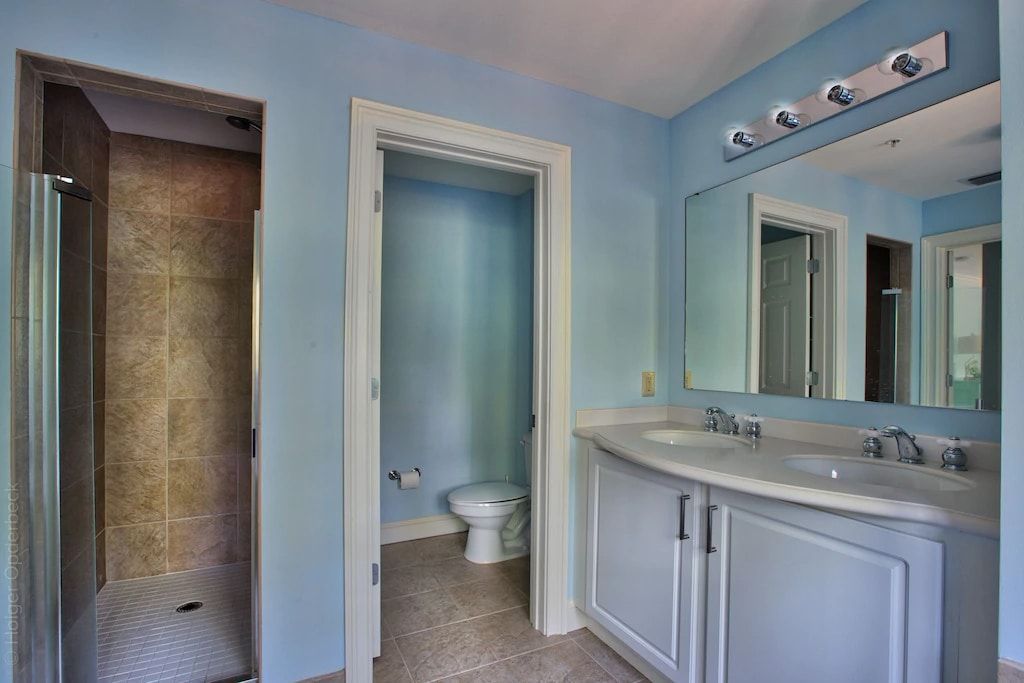 A bathroom with a toilet , sink , mirror and shower.