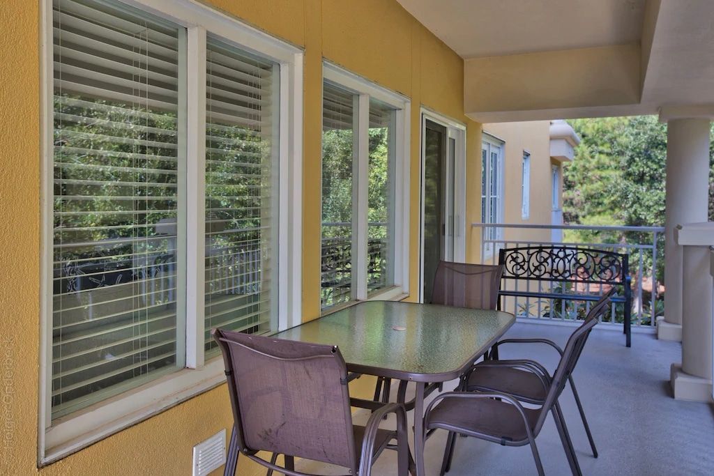 A balcony with a table and chairs and blinds on the windows
