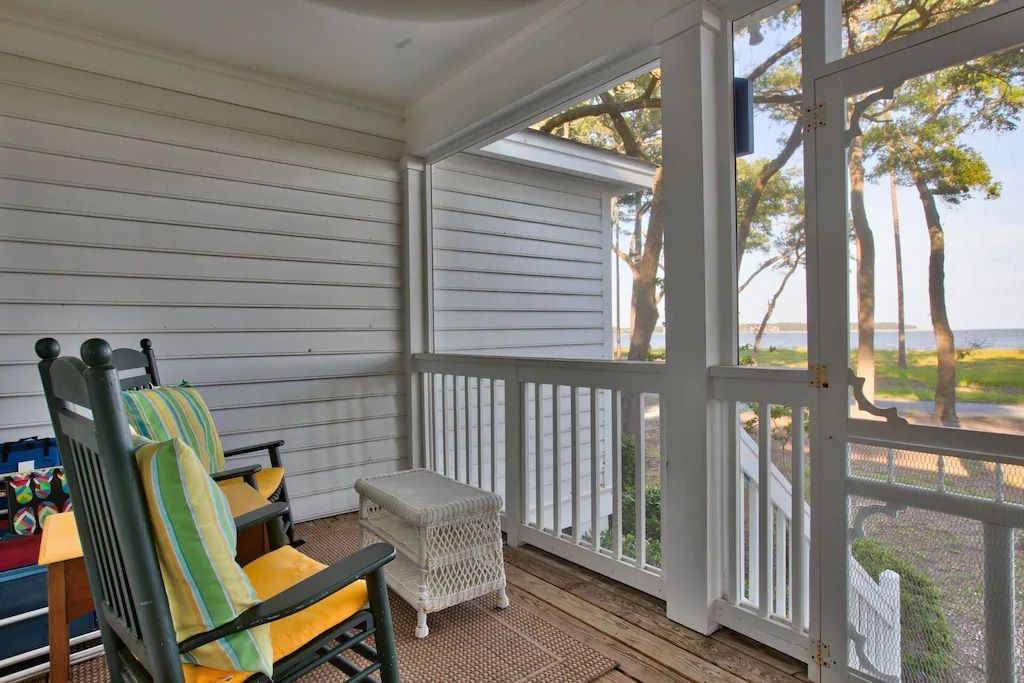 A screened in porch with a rocking chair and a table.